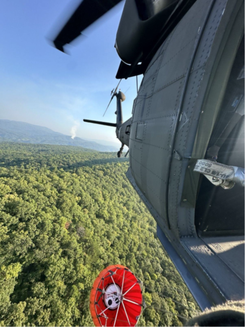 A Tennessee National Guard UH-60 Blackhawk helicopter, from Knoxville’s 1-230th Assault Helicopter Battalion, flies to a nearby river to pick up water with a Bambi Bucket suspended under the aircraft. The hundreds of gallons of water were used to fight wildfires in the Great Smoky Mountains National Park, August 27. (submitted Tennessee National Guard photo) 